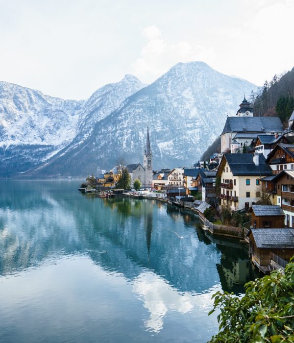 A beautiful shot of a small village surrounded by a lake and snowy hills